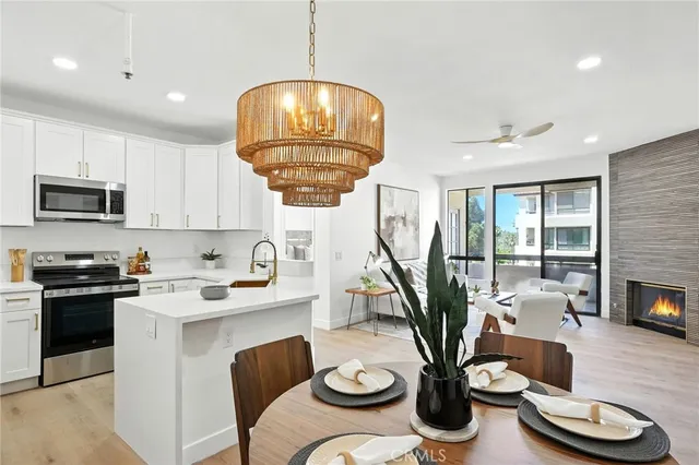 a kitchen with stainless steel appliances granite countertop a stove a kitchen island a dining table and chairs with wooden floor