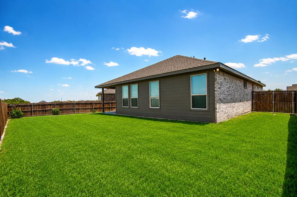 1804 Mensa Drive Haslet, TX 76052 - Photo 27 of 30 Spacious backyard featuring a lush lawn, privacy fencing, and a covered patio area