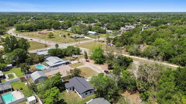 an aerial view of residential houses with outdoor space and trees