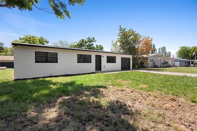 a front view of house with yard and trees in the background