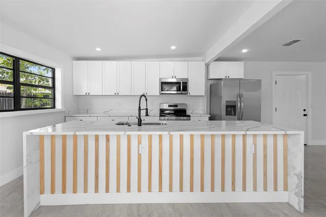 a kitchen with stainless steel appliances sink refrigerator and window