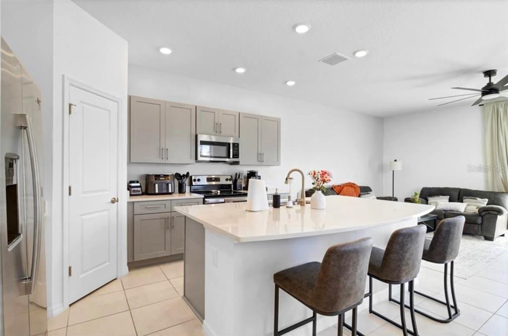 3609 Anibal Street Kissimmee, FL 34746 - Photo 6 of 17 a kitchen with stainless steel appliances a table chairs refrigerator and cabinets