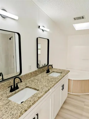 a bathroom with a granite countertop sink a mirror and shower