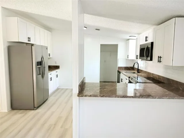 a kitchen with granite countertop a refrigerator sink and cabinets