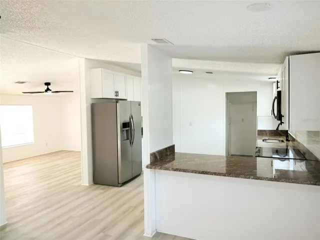 a kitchen with stainless steel appliances granite countertop a refrigerator a sink dishwasher and wooden cabinets with wooden floor