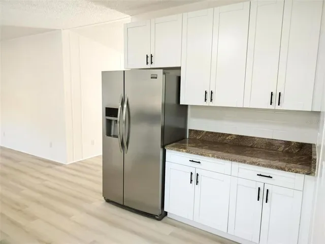a kitchen with granite countertop white cabinets and a stove with wooden floor
