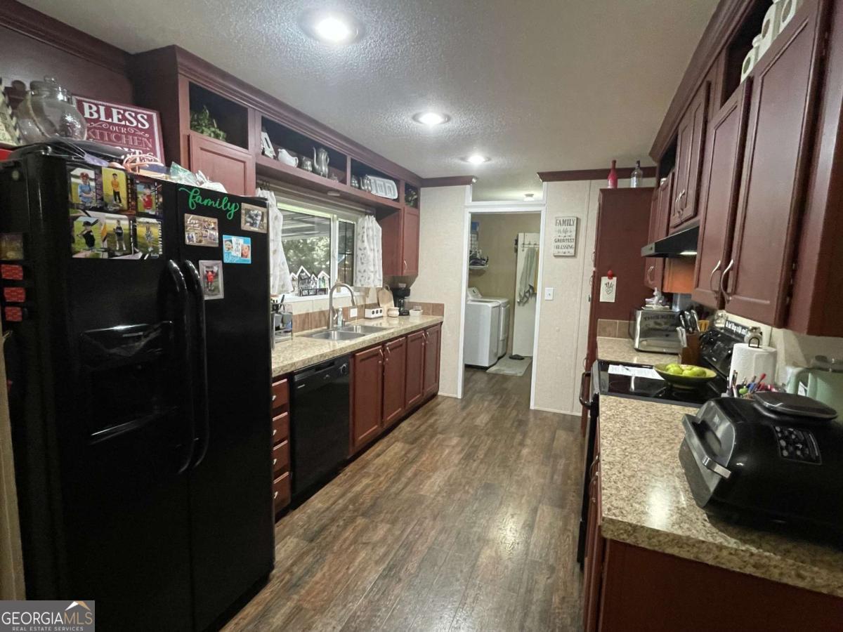601 Auburn Road Glennville, GA 30427 - Photo 9 of 17 a kitchen with stainless steel appliances granite countertop a refrigerator a stove and a wooden floors