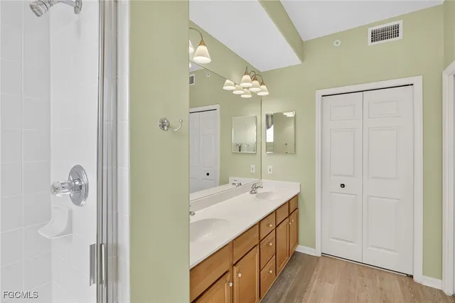 a spacious bathroom with a double vanity sink a large mirror and shower
