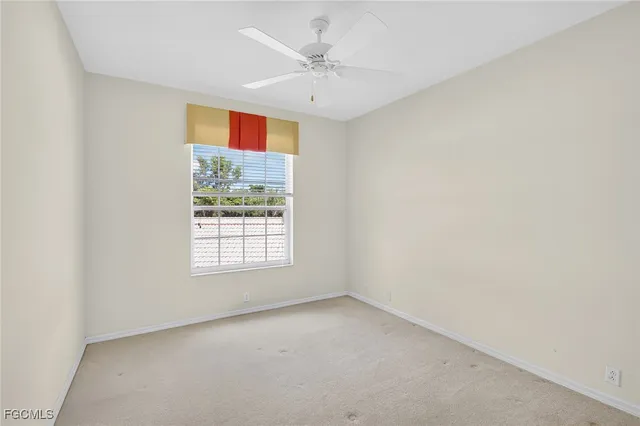 an empty room with windows and a ceiling fan