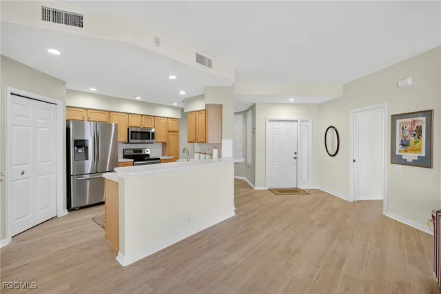 a view of kitchen with stainless steel appliances granite countertop refrigerator sink and wooden floor