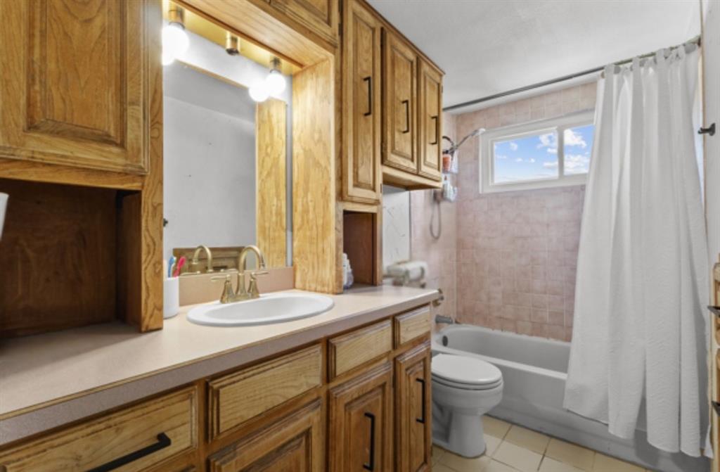 1401 Apache Street Arlington, TX 76012 - Photo 12 of 17 a bathroom with a granite countertop sink toilet a mirror a vanity and shower