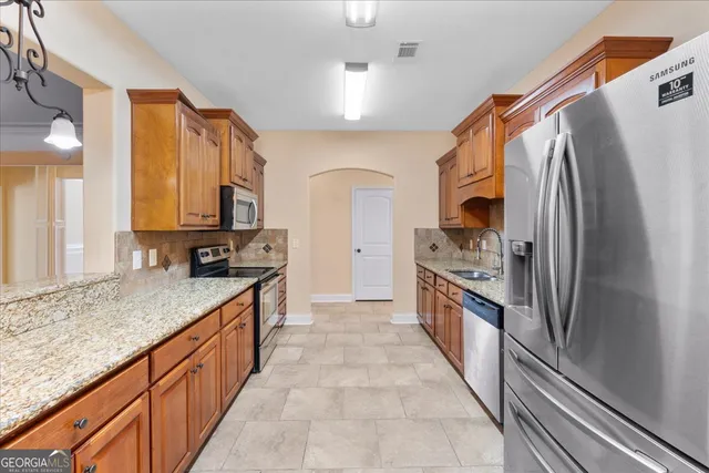 a large kitchen with stainless steel appliances granite countertop a sink and a refrigerator