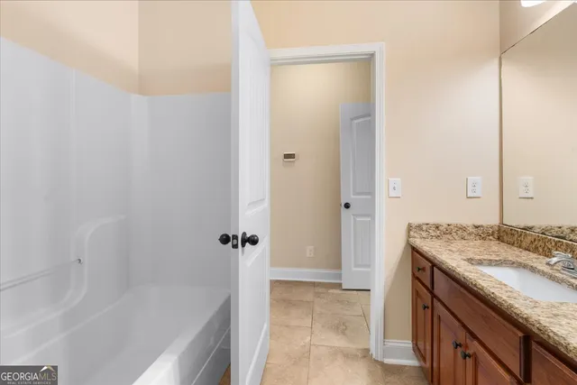 a bathroom with a granite countertop sink a mirror and a bathtub