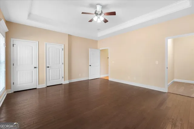 an empty room with wooden floor and ceiling fan