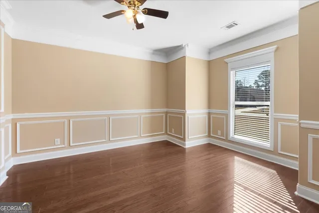 a view of an empty room with a window and wooden floor