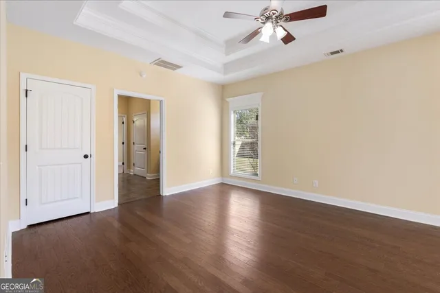 an empty room with wooden floor fan and windows