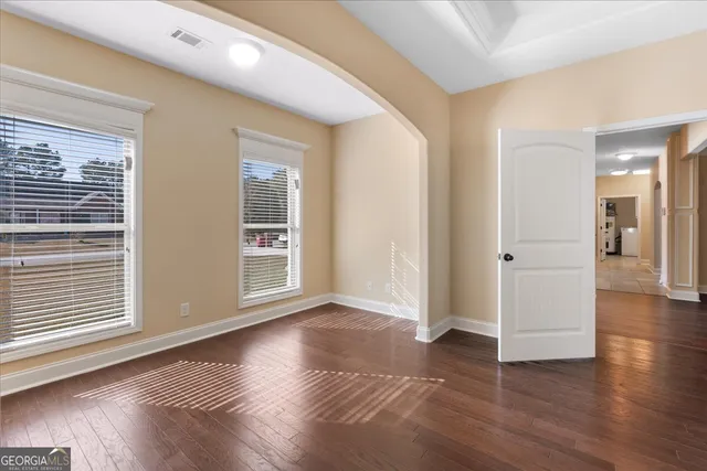 an empty room with wooden floor and windows