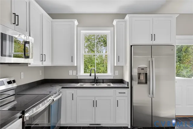 a kitchen with stainless steel appliances granite countertop a refrigerator and white cabinets