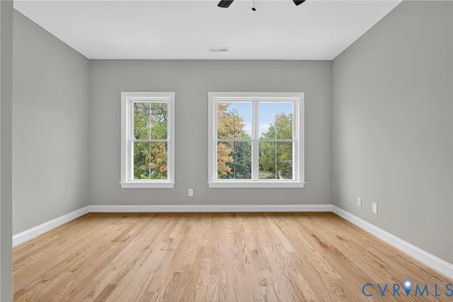 an empty room with wooden floor and windows