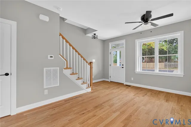 a view of an empty room with wooden floor windows and a ceiling fan