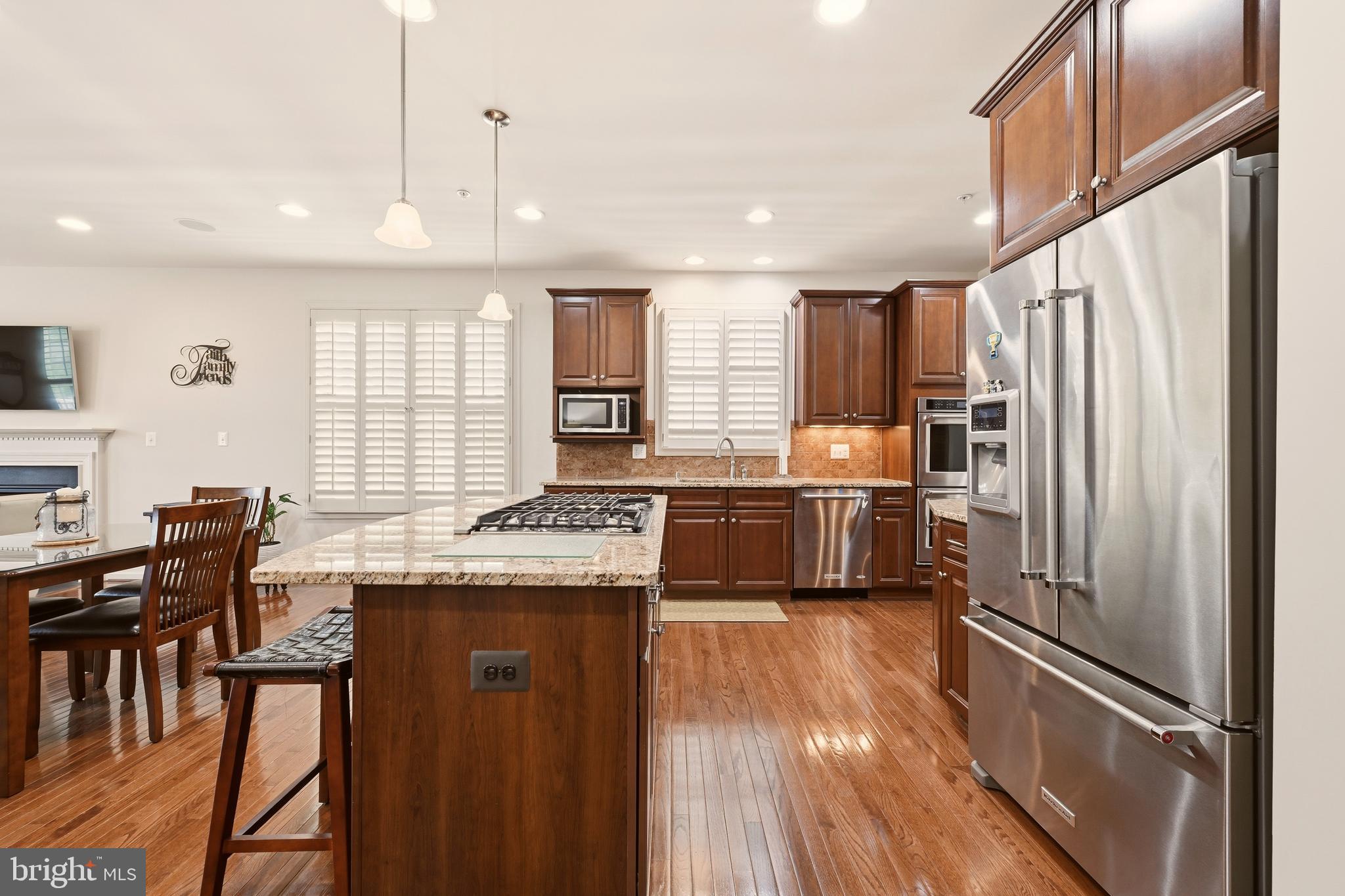 1104 Sweetbay Place Silver Spring, MD 20906 - Photo 13 of 43 a kitchen with granite countertop a refrigerator a sink a stove and chairs with wooden floor