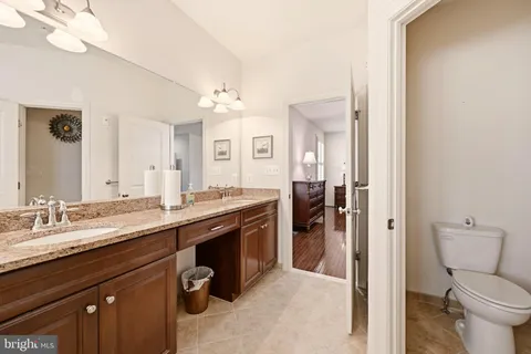 a spacious bathroom with a granite countertop sink a toilet and a mirror