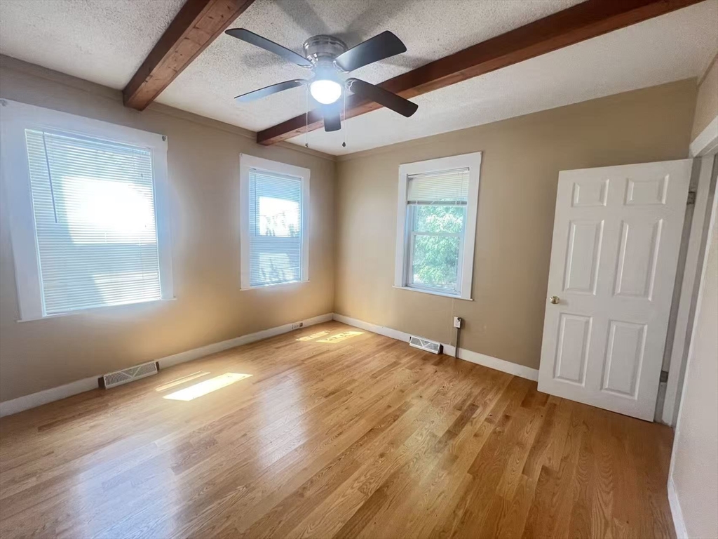 a view of an empty room with a window and wooden floor