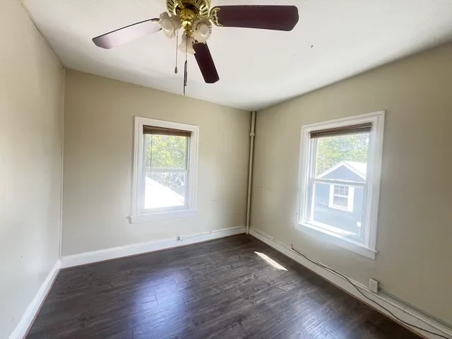 a view of an empty room with wooden floor and window
