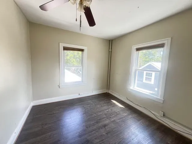 a view of an empty room with wooden floor and window
