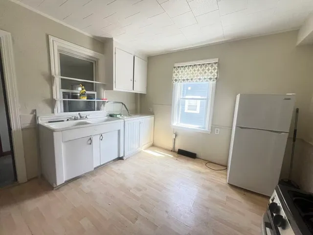 a view of a kitchen with a sink dishwasher a refrigerator and a window