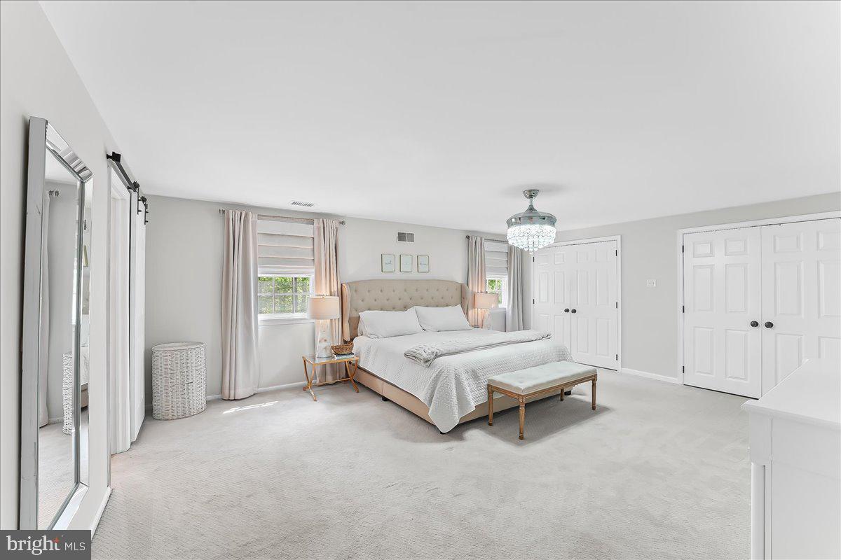 204 Country Gate Road Wayne, PA 19087 - Photo 19 of 34 a spacious bedroom with a bed and a chandelier