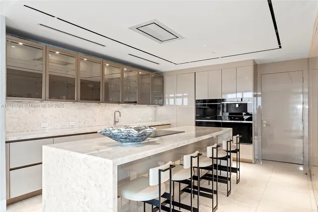 a kitchen with stainless steel appliances kitchen island granite countertop a table chairs and a refrigerator