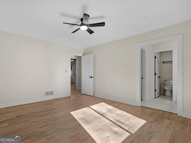an empty room with closet and a ceiling fan