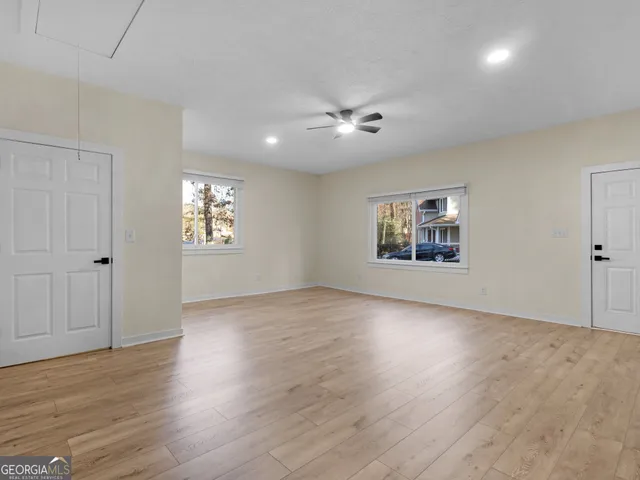 an empty room with wooden floor chandelier and windows