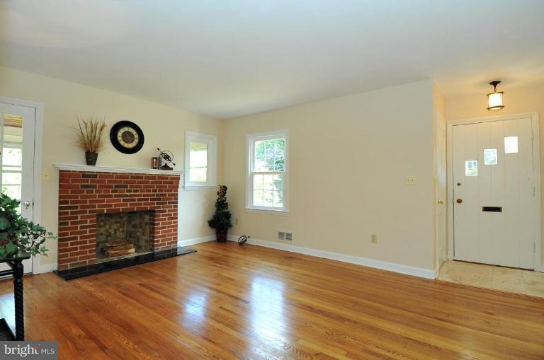 9518 St Andrews Way Silver Spring, MD 20901 - Photo 4 of 29 an empty room with wooden floor fireplace and windows