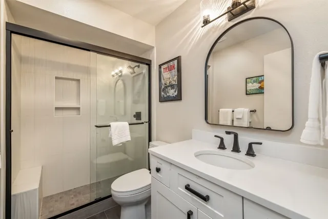 a bathroom with a granite countertop sink mirror vanity and toilet