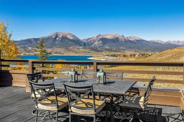 a view of a chairs and table on wooden deck with a lake view