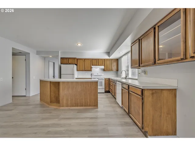 a large kitchen with stainless steel appliances granite countertop a large counter top a stove a sink dishwasher and a refrigerator with wooden floor
