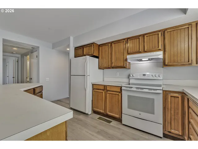 a kitchen with stainless steel appliances granite countertop a refrigerator a stove and white cabinets with wooden floor