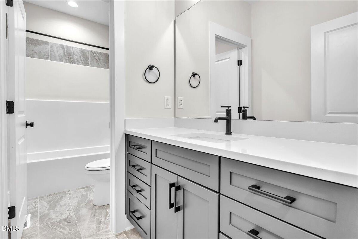 12916 Mallard Rock Road Zebulon, NC 27597 - Photo 29 of 68 a bathroom with a sink a toilet a shower and a mirror