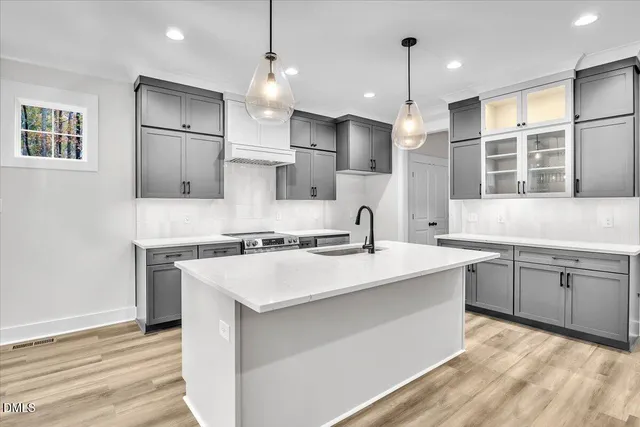 a kitchen with a sink stove and wooden floor