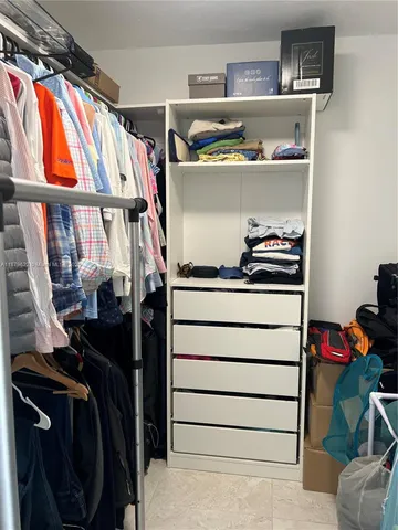 a view of walk in closet with clothes and shoes