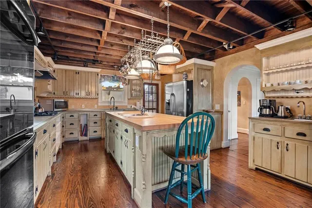 a kitchen with lots of wooden furniture a sink a counter space wooden floor and stainless steel appliances