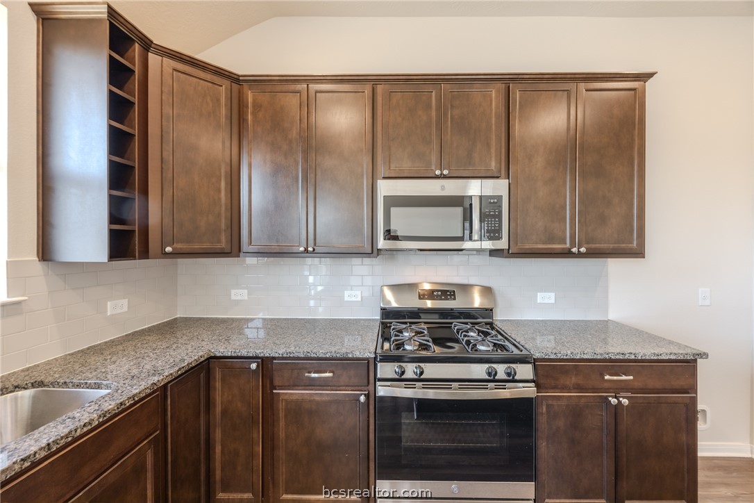 1012 Old Vine Road Brenham, TX 77833 - Photo 11 of 22 a kitchen with granite countertop wooden cabinets and stainless steel appliances