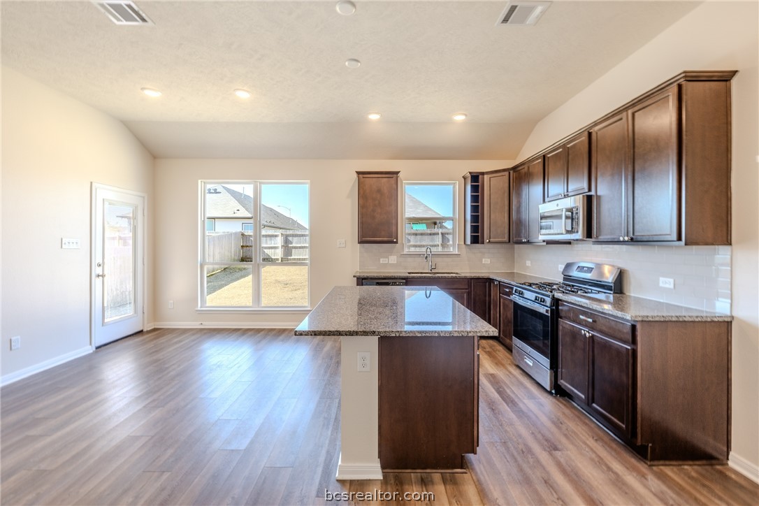 1012 Old Vine Road Brenham, TX 77833 - Photo 8 of 22 a kitchen with stainless steel appliances granite countertop wooden cabinets a stove a sink and a large window