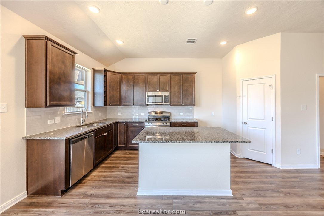 1012 Old Vine Road Brenham, TX 77833 - Photo 9 of 22 a kitchen with stainless steel appliances granite countertop wooden cabinets a sink a stove a refrigerator and island with wooden floor