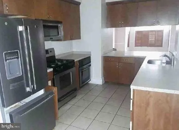a kitchen with stainless steel appliances granite countertop a refrigerator a stove and a sink