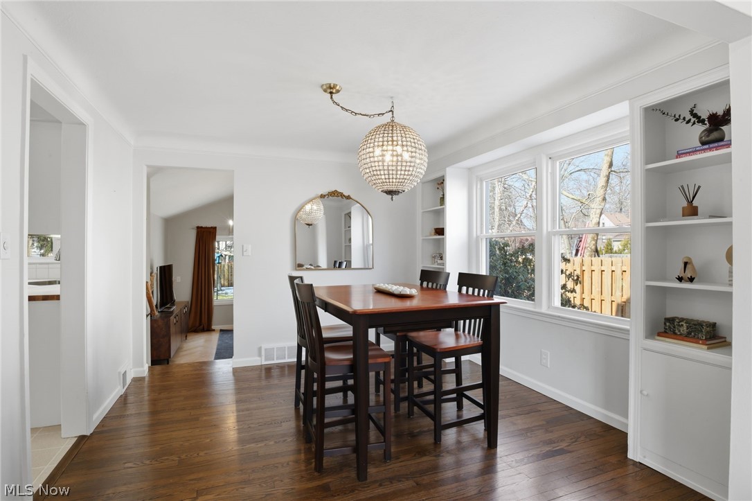 1390 Brainard Road Lyndhurst, OH 44124 - Photo 7 of 33 Dining space featuring dark wood-style floors, plenty of natural light, a chandelier, lofted ceiling, and built in shelves