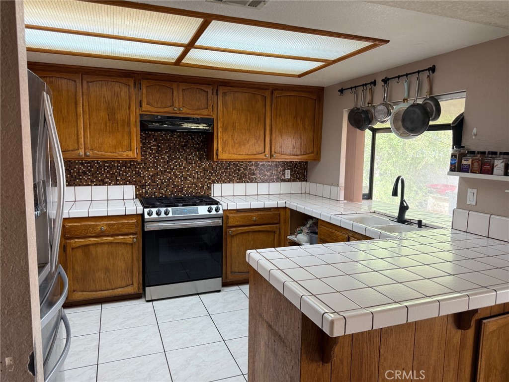 15246 Chaparral Way Victorville, CA 92394 - Photo 2 of 6 a kitchen with a stove a sink and a refrigerator