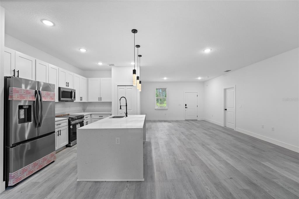 4450 Badali Road North Port, FL 34286 - Photo 4 of 28 a large kitchen with stainless steel appliances kitchen island a large counter top and wooden floors